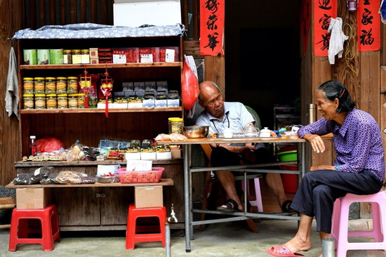 随着游客不断增多，土楼原住民纷纷做起了旅游小生意。图为2017年8月9日，正在等待客人的老爷爷与老奶奶。图源：视觉中国