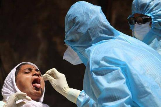 （图说：一名印度女子正在接受核酸检测。图源/GETTY IMAGES）