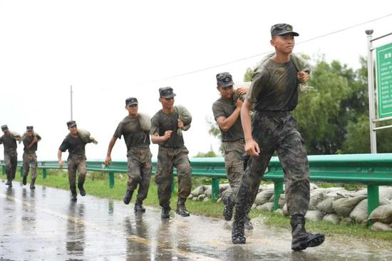  7月24日，驻杭某部93名官兵来到巢湖大堤烔炀段，冒雨垒筑3公里“防浪堤”，确保S601省道畅通。记者 方娟 苏玲 摄