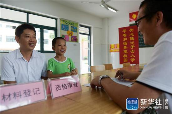 ↑在合肥市和平小学花冲分校报名点，毕权航和父亲毕金仓（左）在办理报名入学相关手续（2017年7月12日摄）。 当日，合肥市瑶海区进城务工人员随迁子女入学报名工作启动。新华社记者 张端 摄