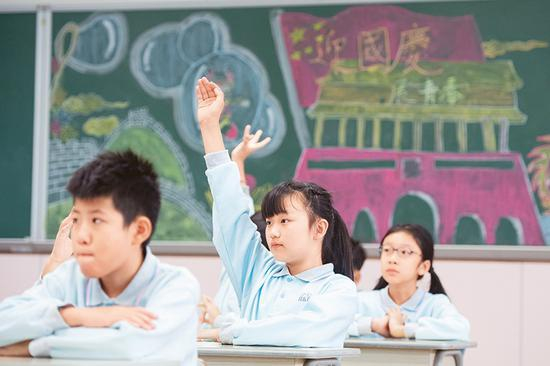 澳门中小学学生使用的教材《品德与公民》中有丰富的关于国情、国旗、国歌的内容，学生们可以从中学到很多关于祖国的知识，培养对祖国和澳门的感情。图为2019年11月25日，澳门濠江中学附属英才学校的学生在课堂上举手回答老师提问。 新华社记者 张金加/摄
