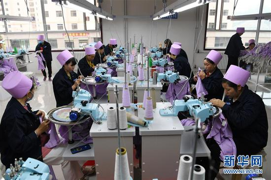 在甘肃省临夏回族自治州东乡族自治县城南区易地扶贫搬迁安置小区的扶贫车间，留守妇女在制衣车间工作（8月4日摄）。新华社记者 范培珅 摄