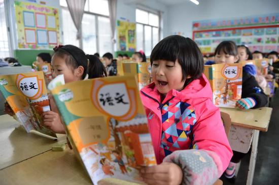 小学生在开学第一课上阅读语文教材 杨韬 摄