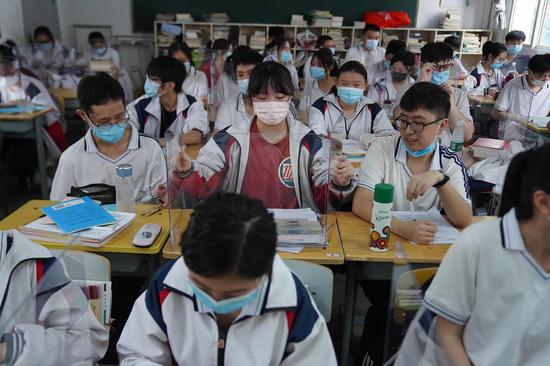 　　2020年7月10日，武汉，学校在课桌上放置了透明小隔板，为了保持学生之间坐在课桌前的社交距离。人民视觉 图