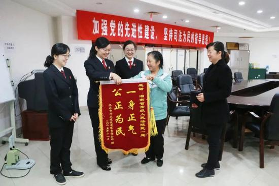  周春梅（左二）在法院接收锦旗。图片来源：湖南高院