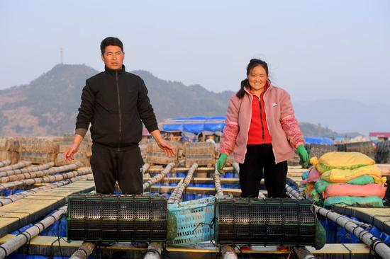 “春运母亲”巴木玉布木与丈夫巫其石且从四川凉山彝族自治州老家辗转来到福建省霞浦县溪南镇海域，从事海上渔排海参养殖。这是2月4日在渔排上拍摄的巴木玉布木（右）与丈夫巫其石且。新华社记者 姜克红 摄