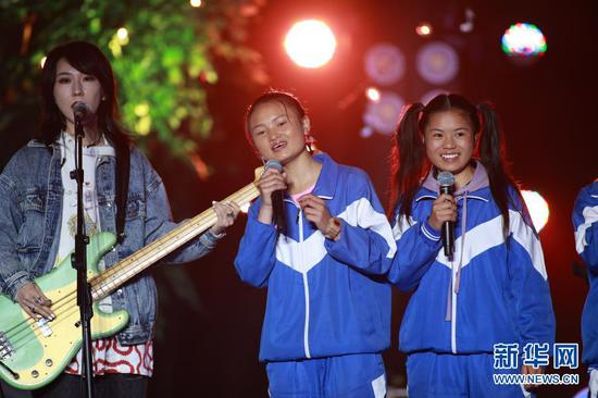 “遇”乐队吉他手李美银（中）和鼓手罗丽欣（右）在“海嘎少年的夏天”音乐会上和新裤子乐队一起演出（2020年8月19日摄）。当晚，在海拔2400米的贵州韭菜坪山腰上的六盘水市钟山区大湾镇海嘎小学，由海嘎小学的同学组成的“遇”乐队、“未知少年”乐队和颇受年轻人喜欢的摇滚乐队新裤子乐队一起演出了一场名为“海嘎少年的夏天”线上音乐会。新华社记者 刘续 摄