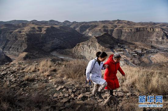 路生梅（右）与同事一起去佳县店镇贺家沟村一名卧床不起的病人家义诊途中（2月4日摄）。新华社记者 陶明 摄