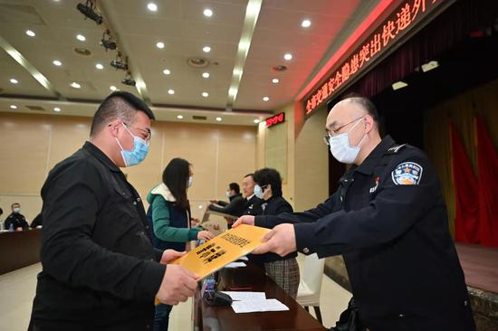  快递企业代表接过“重大交通安全隐患”警示牌。摄影/甘南