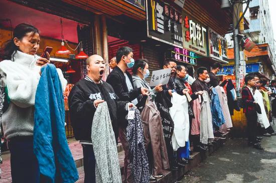 2021年 3月3日，元宵节之后的工作日，广州康乐村街头，制衣厂的老板们排成一列，手里拿着样板招募前来务工人员。图/人民视觉