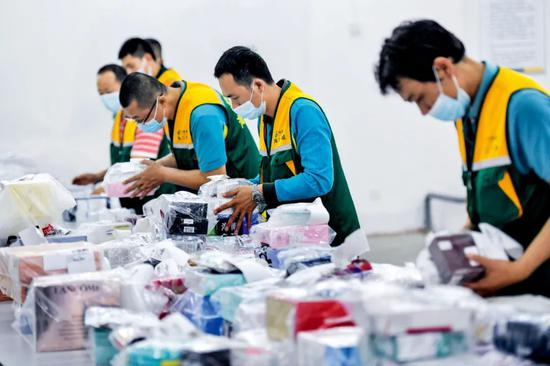 3月4日，在中国邮政集团公司海口市分公司离岛免税品邮寄送达处理中心，工作人员正在给即将邮寄的免税品进行消毒杀菌作业。摄影/本刊记者 骆云飞