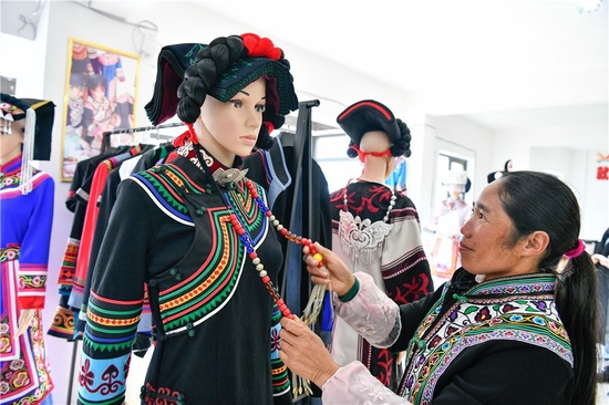 在贵州省毕节市威宁县五里岗街道朝阳新城易地扶贫搬迁安置小区，搬迁户在就业扶贫手工车间整理缝制完毕的民族服饰（2021年11月28日摄）。新华社记者 杨文斌 摄