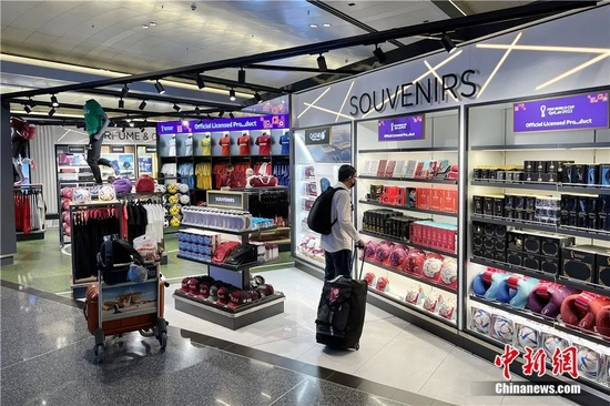 旅客在哈马德国际机场内的2022年世界杯纪念品商店中挑选纪念品。崔楠 摄