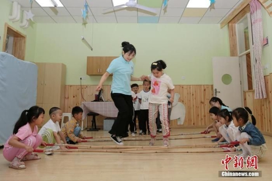 　资料图：老师带领孩子们在教室内游戏。中新社记者 张远 摄