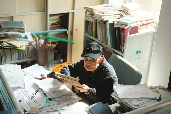  ·沈燮元埋头在满桌的书本资料中。