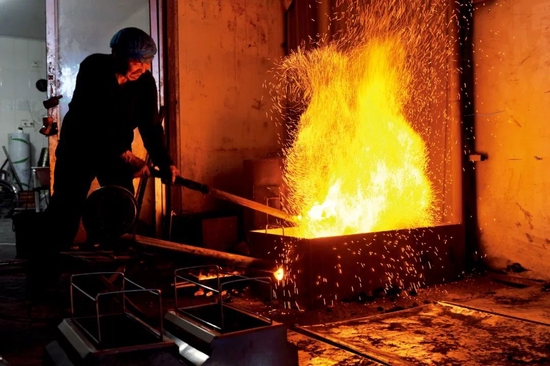  3月21日，淄博一家烧烤店的烧炭工正用鼓风机加工木炭。这些烧红的木炭会配给食客桌上的小炉子内。图/视觉中国