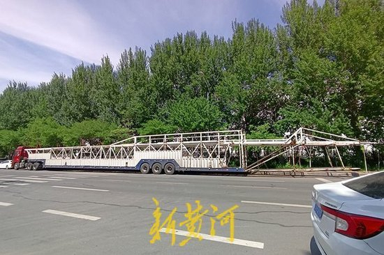 一辆平头轿运车停靠在宝来街，总长度超过40米