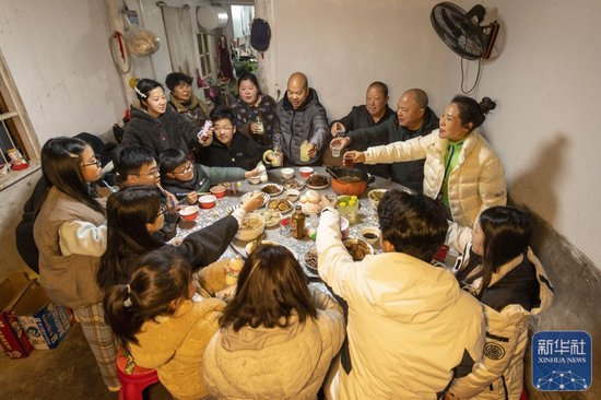  ↑ 2月16日，在浙江省永康市花街镇山后胡村，村民陈其虎一家四代同堂吃年夜饭。新华社发（胡肖飞 摄）