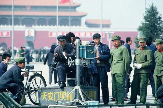 △ 1978年，北京，军人在天安门广场上的国营拍照点等待照相。