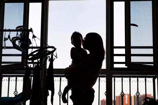  6月8日，魏圆圆抱着儿子站在阳台上。新京报记者陶冉 摄