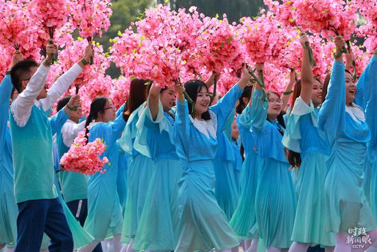 　　△第二篇章“改革开放”第3个方阵“春潮滚滚”，男女青年手持花束走过天安门广场。（央视记者李峻拍摄）