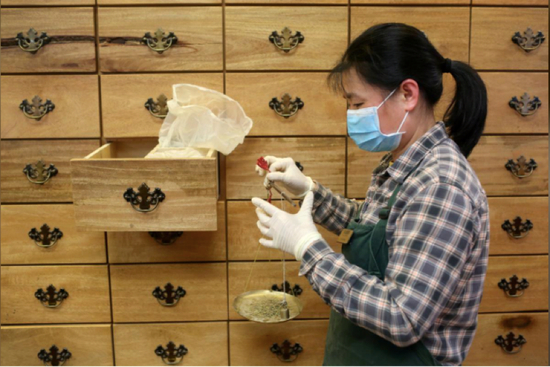 △Kamwo药店的店员给药材称重 来源：路透社