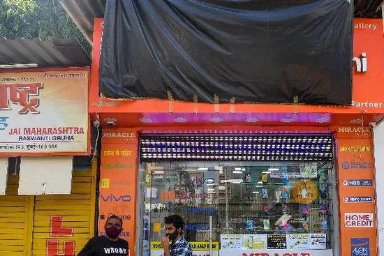 ▲6月25日，印度孟买一家售卖电子产品的商铺用布将印有中国手机品牌标识的招牌遮住。（法新社）
