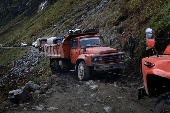  墨脱境内的一辆卡车牵引陷入淤泥的货车。&nbsp;