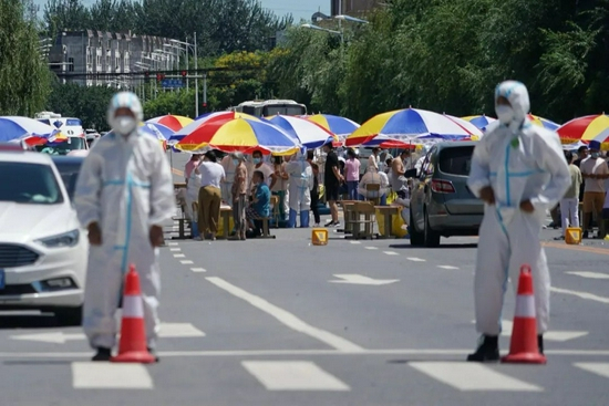 马路中央支起了遮阳伞，居民正排队接受核酸检测。