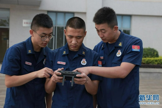 高强（中）正在和同事一起操纵无人机（摄于7月27日）。新华网 刘东 摄