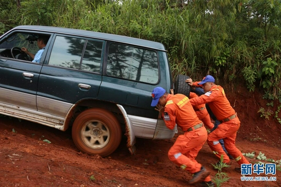 雨天车辆打滑，森林消防员们在推车（摄于7月29日）。新华网 刘东 摄