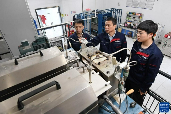 福建闽江学院服装与艺术工程学院教授李永贵（中）在“福建省新型功能性纺织纤维及材料重点实验室”教学生做纺丝实验（3月22日摄）。新华社记者 林善传 摄