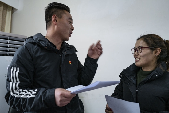  铁忠福（左）在昂仁县与同事交流工作（2021年12月21日）。新华社记者 孙瑞博 摄