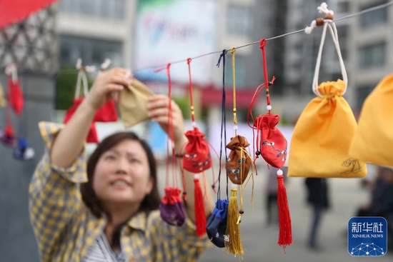 6月2日，贵州省毕节市七星关区青龙街道办事处职工在悬挂香囊。新华社发（韩贤普摄）