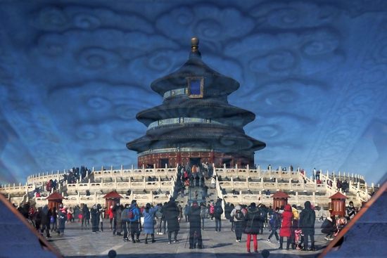 这是2021年2月17日通过玻璃反光拍摄的游客在天坛公园参观游览（照片旋转180度）。新华社记者 鞠焕宗 摄