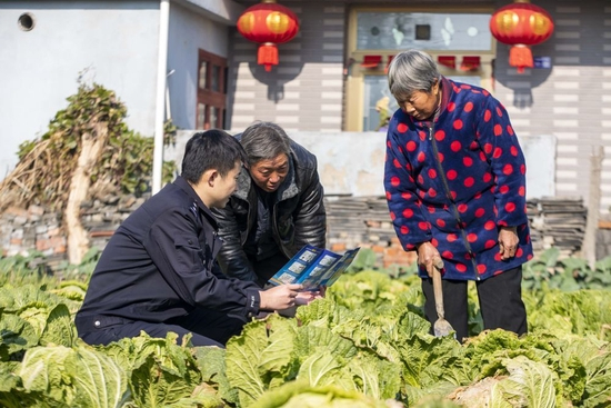 江苏省泰州市海陵区苏陈派出所民警在苏陈社区田间地头向农户进行普法宣传（2021年12月4日摄）。新华社发（汤德宏 摄）