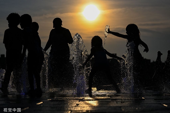 当地时间2022年7月24日，美国纽约，孩子们在布鲁克林多米诺公园喷泉中玩耍降温，身后是曼哈顿天际线。据美国国家气象局称，7月24日晚上8点前，美国纽约市五个区都处于高温预警状态。视觉中国 资料图