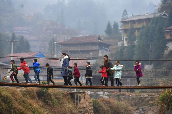 在位于广西融水苗族自治县和贵州省从江县交界的乌英苗寨，郑昌昊（右三）和妻子吴晗（左五）带着孩子们玩耍（2021年1月30日摄）。郑昌昊是广西柳州市委宣传部干部，曾于2020年4月至2021年5月在乌英苗寨担任驻村工作队队员，吴晗曾多次到乌英苗寨教学点支教。新华社记者 黄孝邦 摄