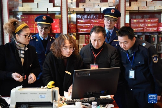 在浙江省宁波市北仑区，联合检查组的工作人员在一家烟酒商店浏览发票记录，核查是否有违规公款消费等情况（2020年1月8日摄）。新华社记者 黄宗治 摄