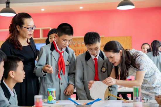 邱燕珍（右一）走进校园传授团扇技艺（央广网发 何丽红 摄）