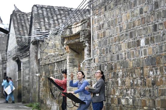  在广西柳州市柳城县古砦仫佬族乡的传统村落大户村滩头屯，绘画爱好者在民居旁写生（2023年4月10日摄）。新华社发（黎寒池 摄）