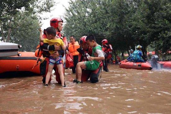  △8月3日，河北涿州北二环附近，山东消防救援人员抱着孩子通过积水路段。