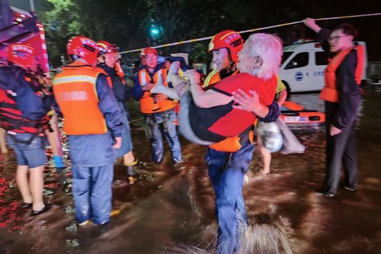▲2023年7月31日，北京市消防救援支队在房山区开展救援。图为消防队员怀抱老人离开积水区。图/房山消防