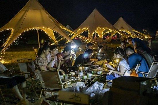  8月8日，在海南省瓊海市，市民和游客在萬泉河畔露營納涼。新華社發（蒙鐘德 攝）