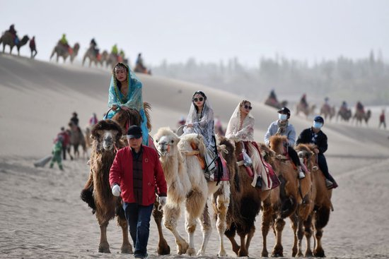 驼队载着游客行走在鸣沙山月牙泉景区的驼道上（2023年4月24日摄）。新华社记者 陈斌 摄