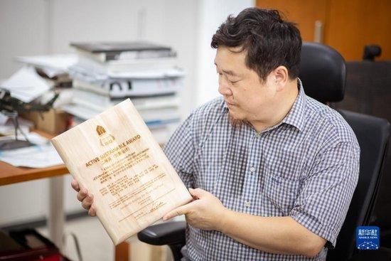 9月12日,在武汉中南建筑设计院总部,唐文胜展示中部非洲文化艺术中心设计方案获奖奖牌。新华社记者 伍志尊 摄