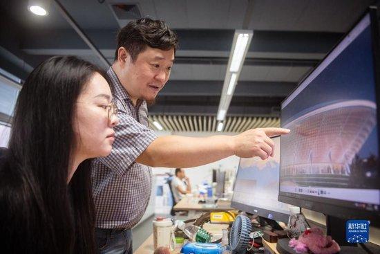 9月12日,在武汉中南建筑设计院总部,唐文胜(右)与同事交流中部非洲文化艺术中心设计方案。新华社记者 伍志尊 摄