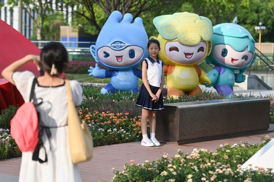 2023年8月21日，小朋友在位于杭州市拱墅区的武林广场与杭州亚运会吉祥物合影。新华社记者 黄宗治 摄