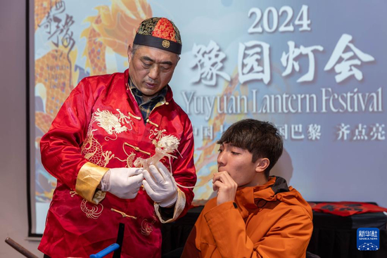  1月28日，在上海豫园举行的民俗活动上，美国马斯卡廷中学学生在非遗传承人的指导下吹糖偶。 新华社记者 王翔 摄