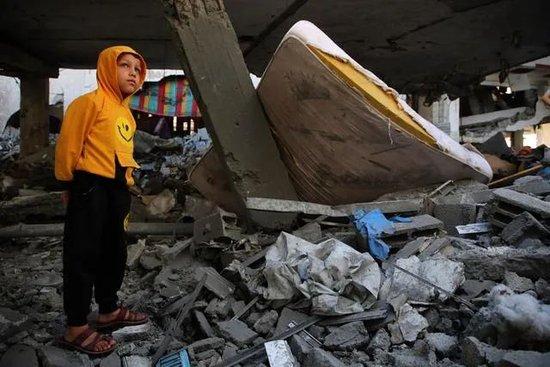  4月17日，在加沙南部城市拉法，男孩站在遭以军空袭的住宅废墟上图：新华社
